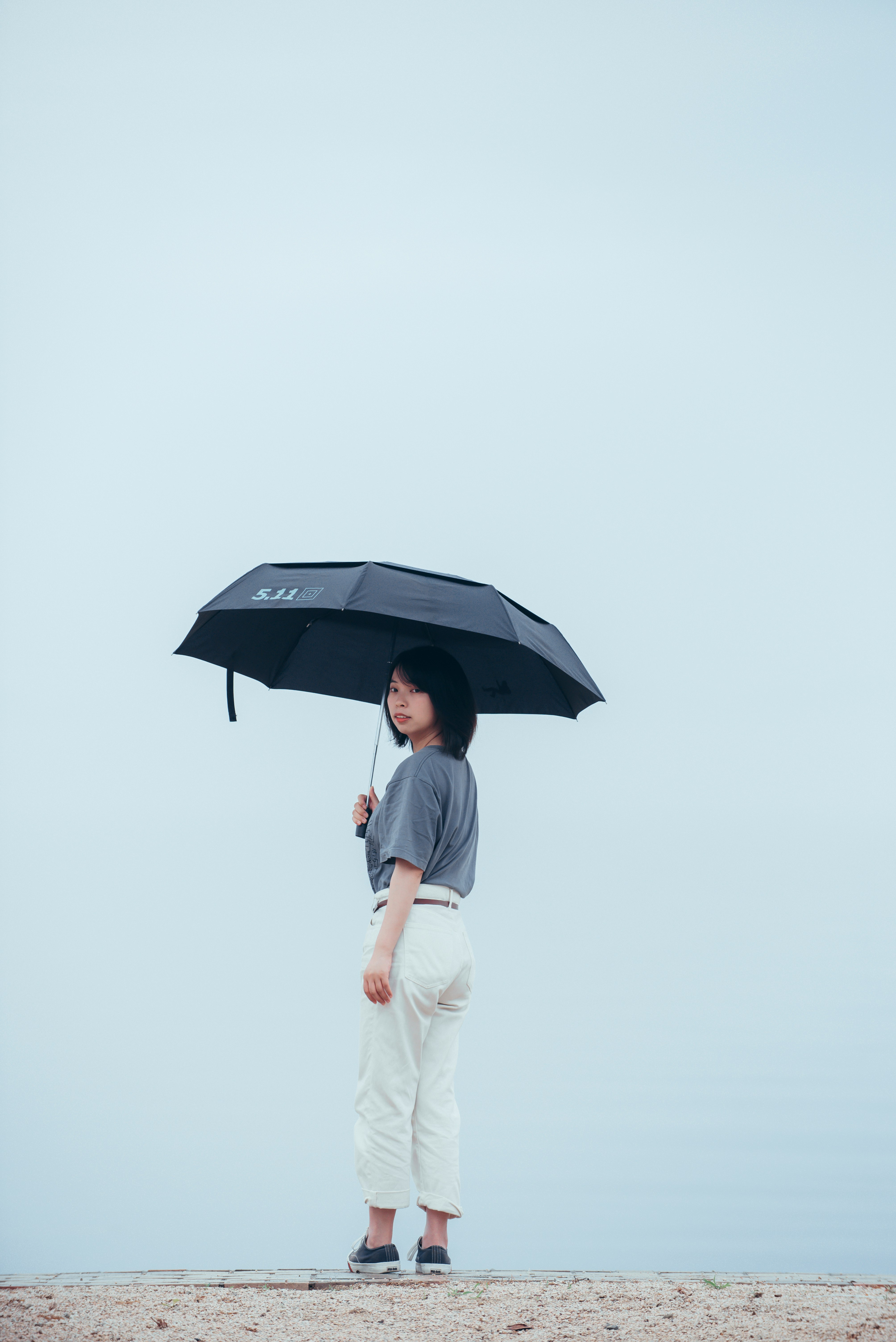 man in white shirt and white pants holding umbrella